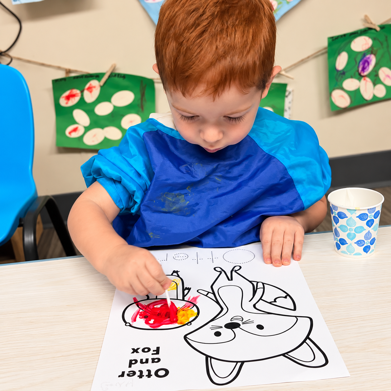 A Pre-K child painting a learning worksheet at Kidz-Zona